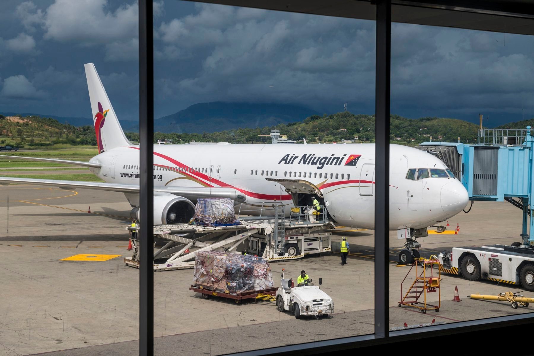 Air Niugini jet being loaded at Port Moresby airport, seen through the terminal window