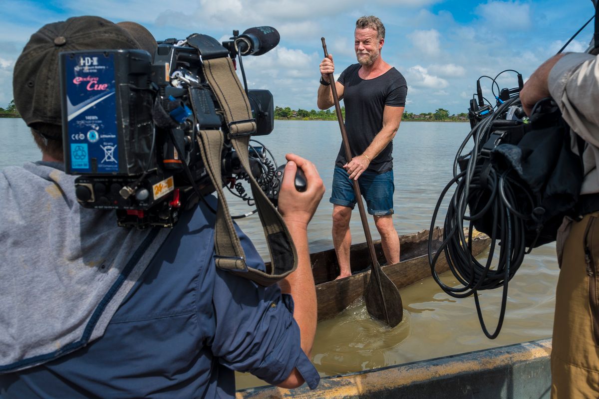 Cameraman and sound recordist filming a presenter poling a dugout canoe