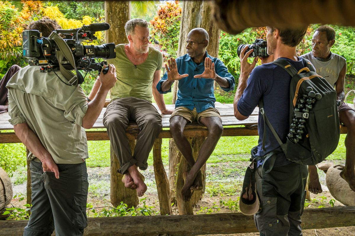 Crew filming an interview in a Sepik village, camera and stills photographer at work