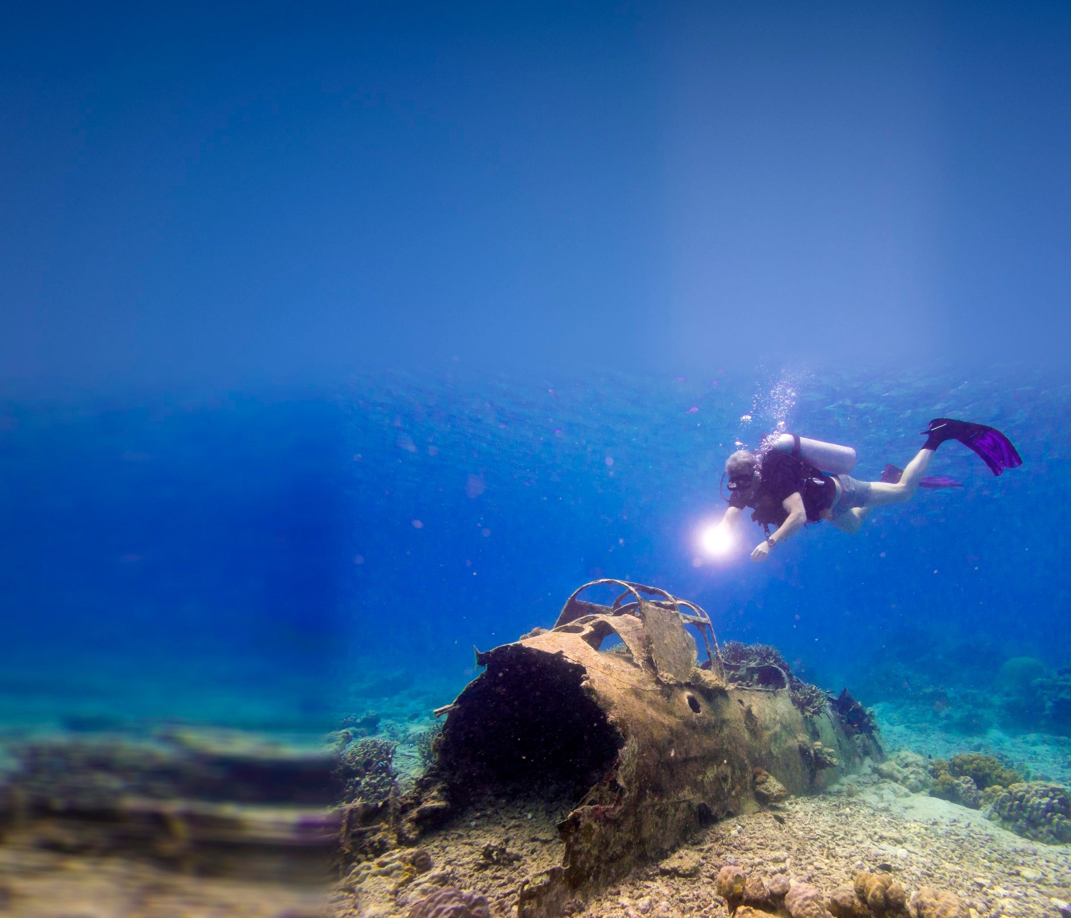 Diver exploring a Second World War aircraft wreck on the reef
