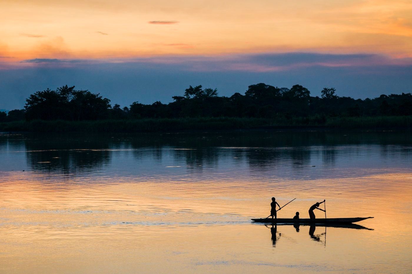 Dugout canoe crossing a river at sunset