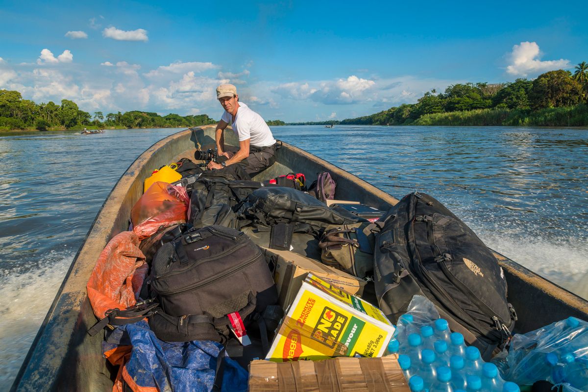 Photographer in a motorised canoe loaded with crew kit on the Sepik River
