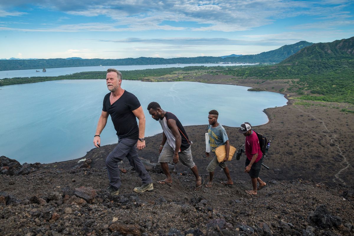 Presenter climbing a volcano above Rabaul harbour with local guides