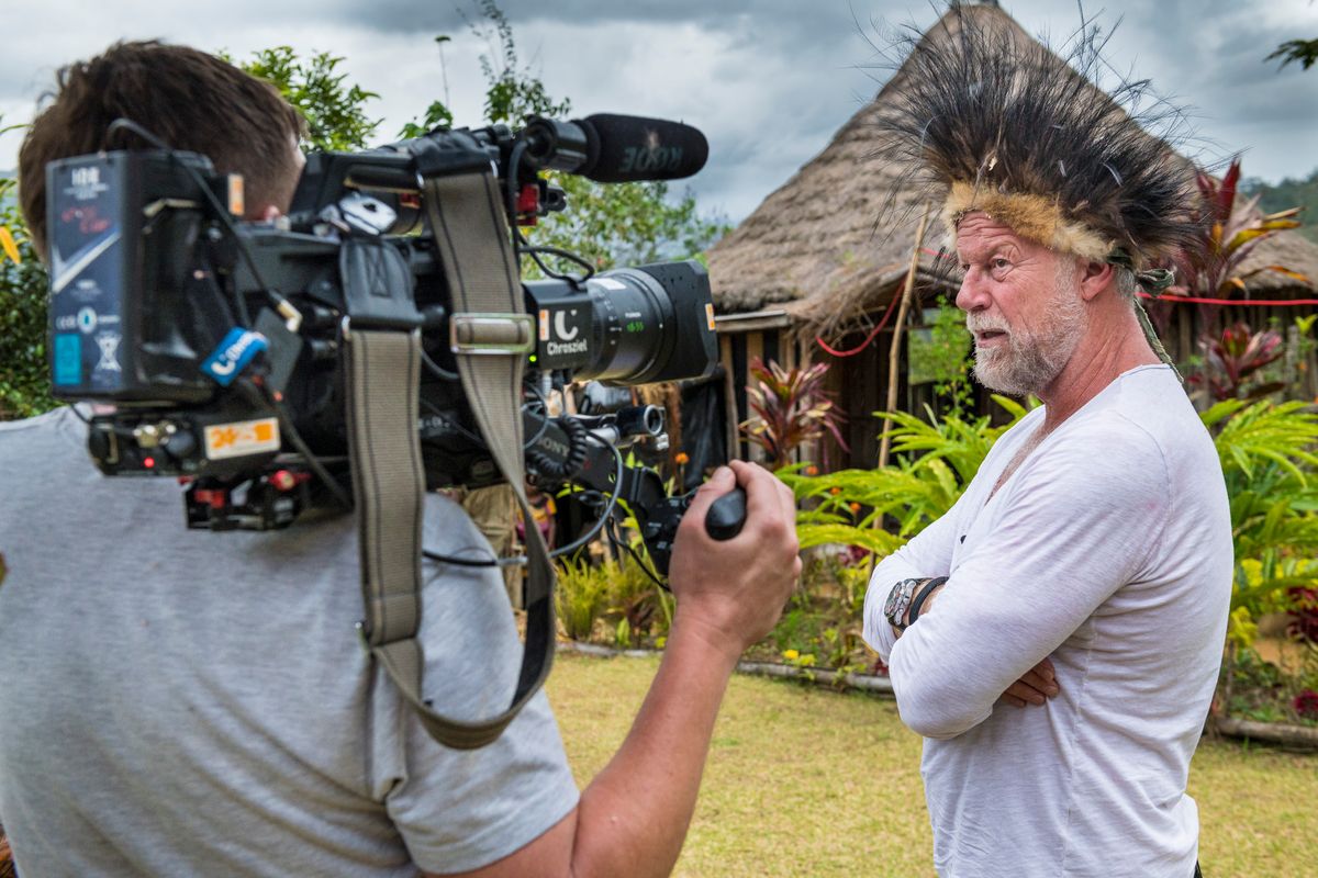 Presenter wearing a Huli feather headdress interviewed by a cameraman