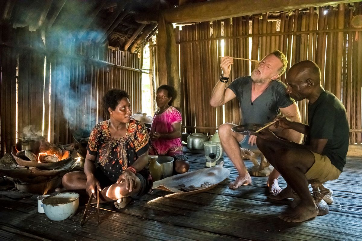 Presenter tasting sago in a Sepik stilt house